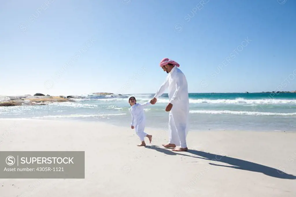 Arab father and son walking at the beach.