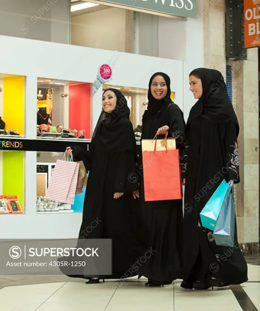 Three young arab women with shopping bags walking in the mall.