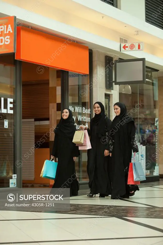 Three young arab women with shopping bags walking in the mall.