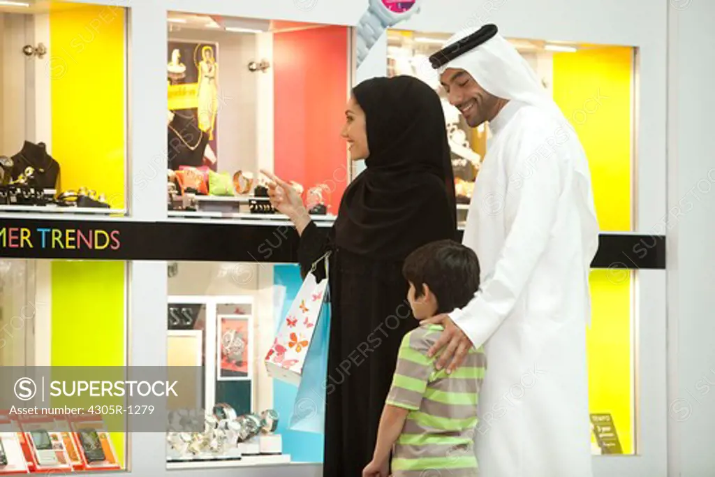 Arab family at the shopping mall, woman pointing on the jewelry display.
