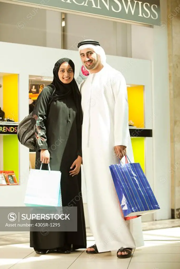 Portrait of arab couple with shopping bags at the mall, smiling.