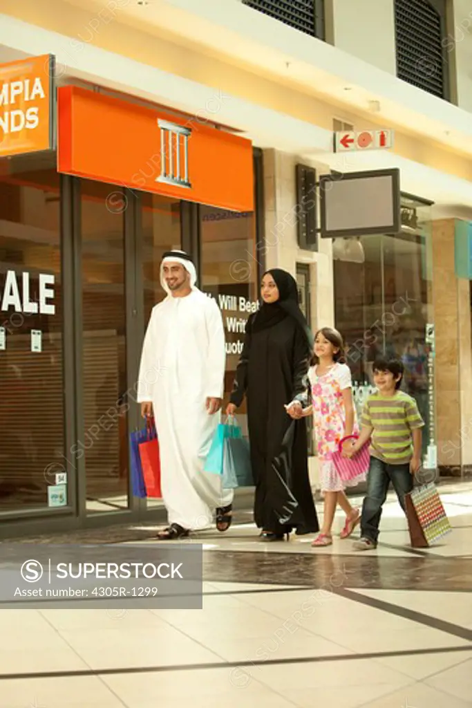 Arab family holding hands while walking in the shopping mall.