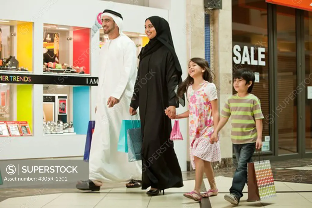 Arab family holding hands while walking in the shopping mall.