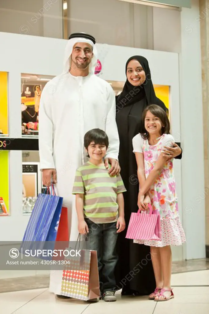 Portrait of arab family standing in the shopping mall, smiling.