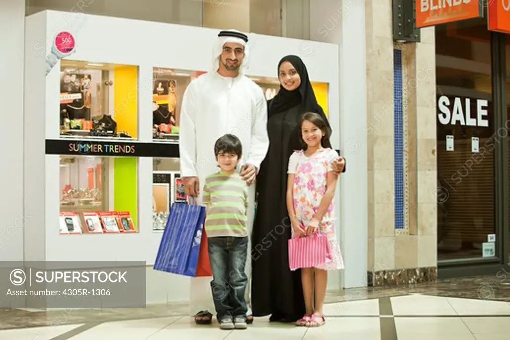Portrait of arab family standing in the shopping mall, smiling.