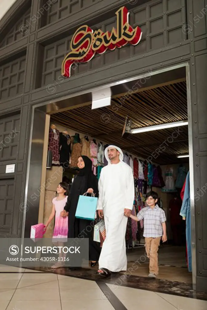 Arab family with shopping bag coming out of the middle eastern shop.