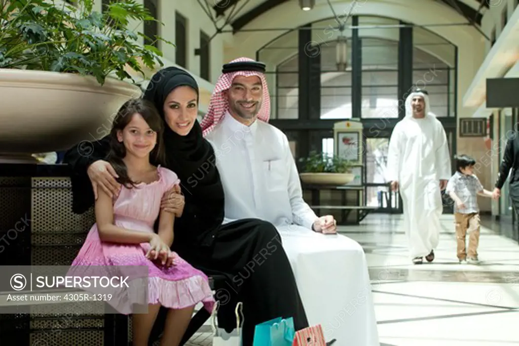 Portrait of arab family sitting at the shopping mall, smiling.