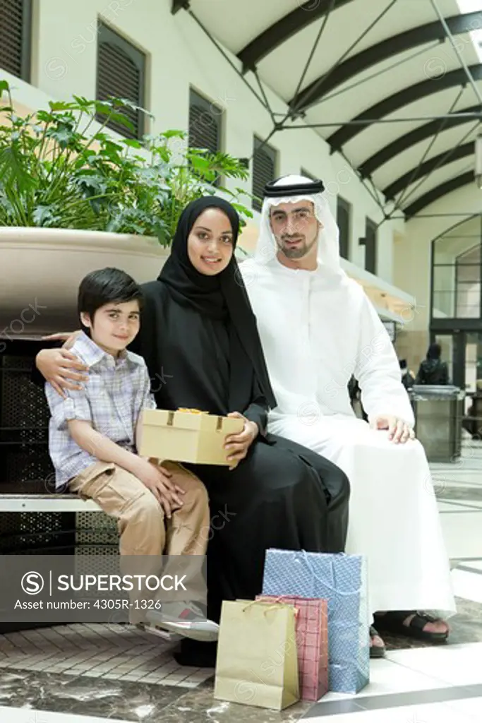 Portrait of arab family with gifts sitting at the shopping mall.