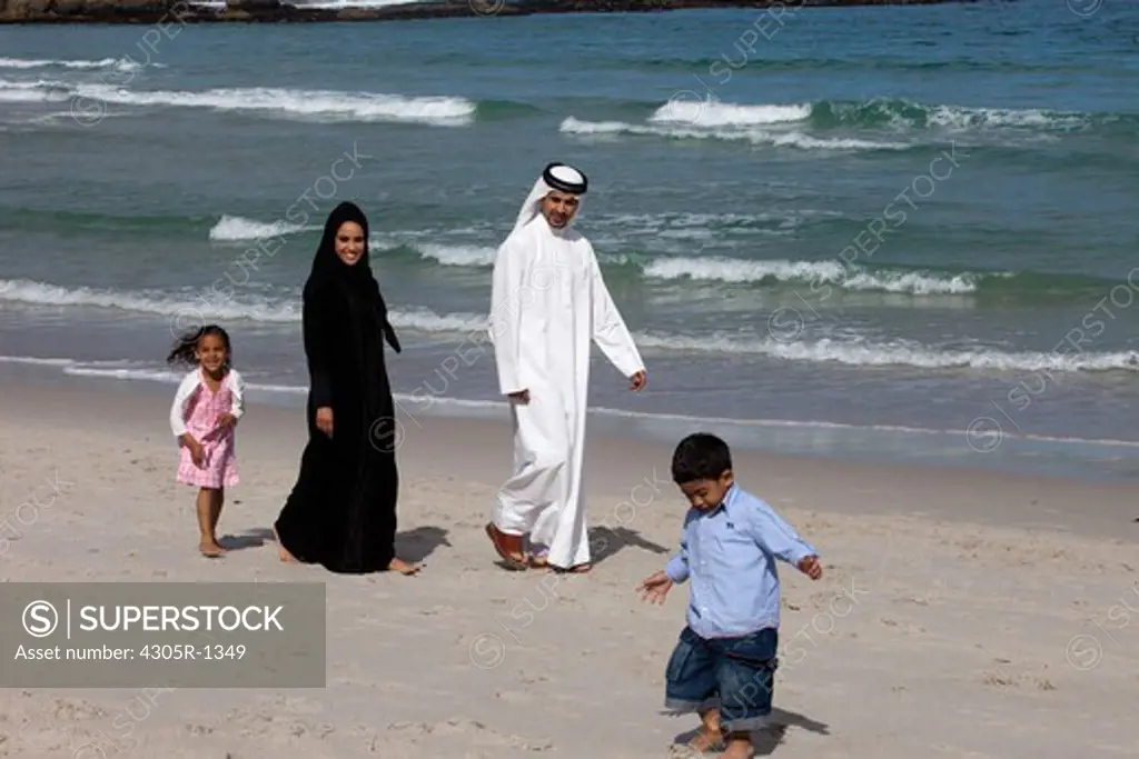 Arab family at the beach, children running on the sand.