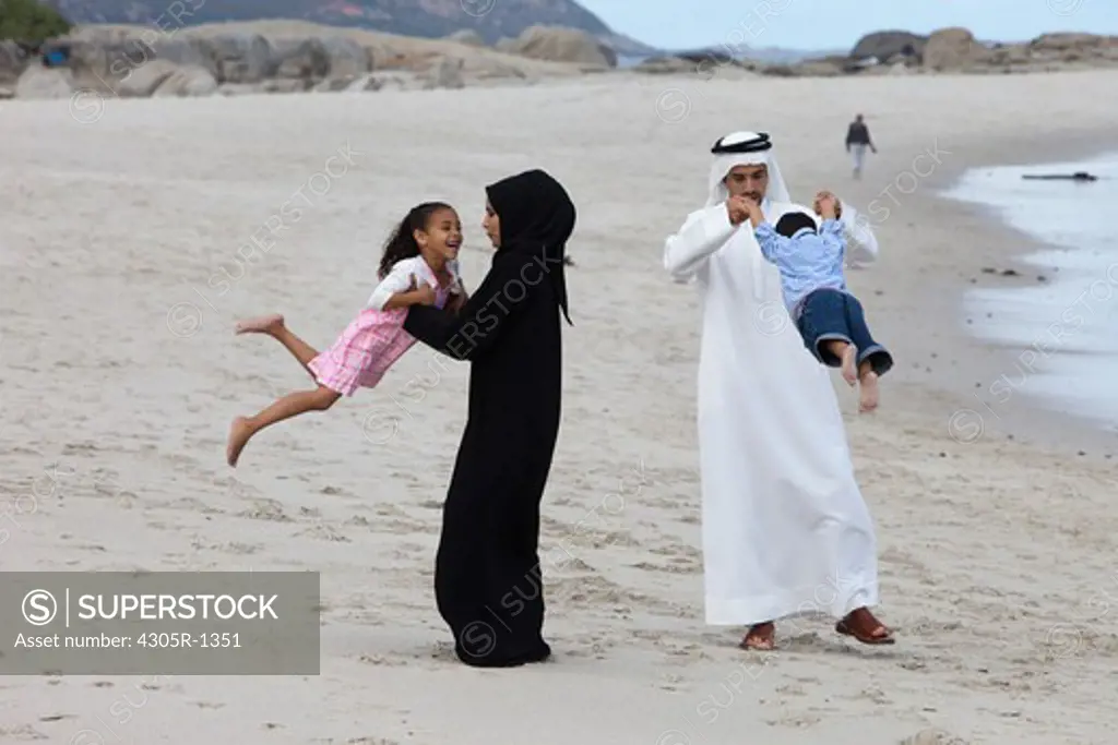Arab family at the beach, parents playing with children.