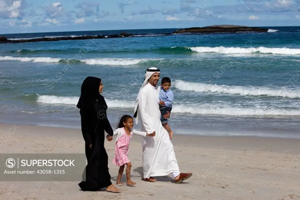 Arab family walking together at the beach.