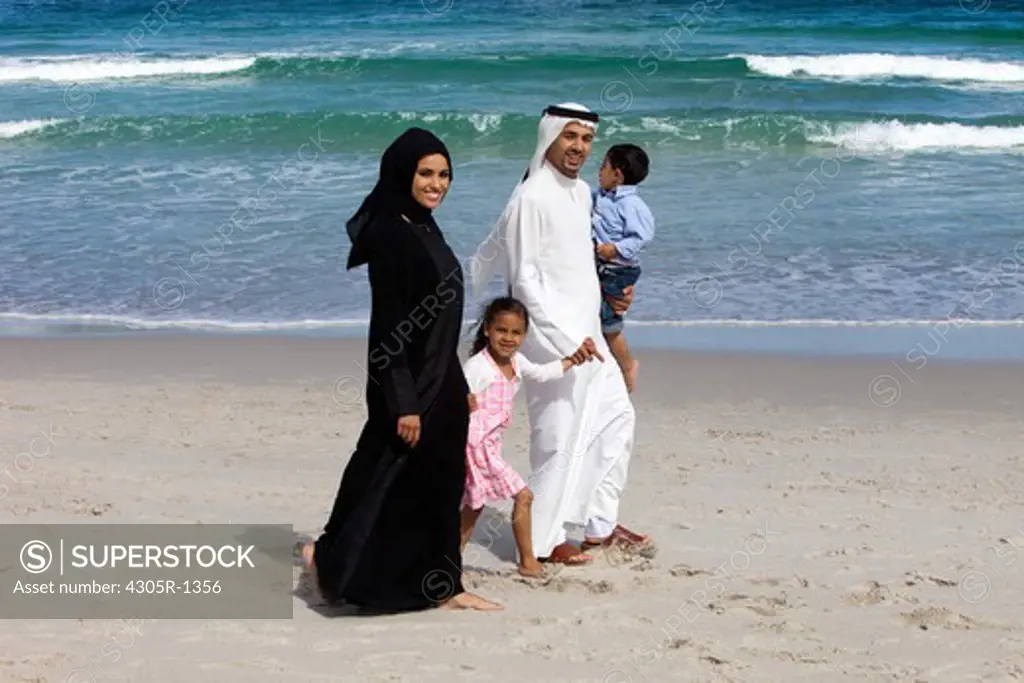Arab family walking together at the beach, smiling.