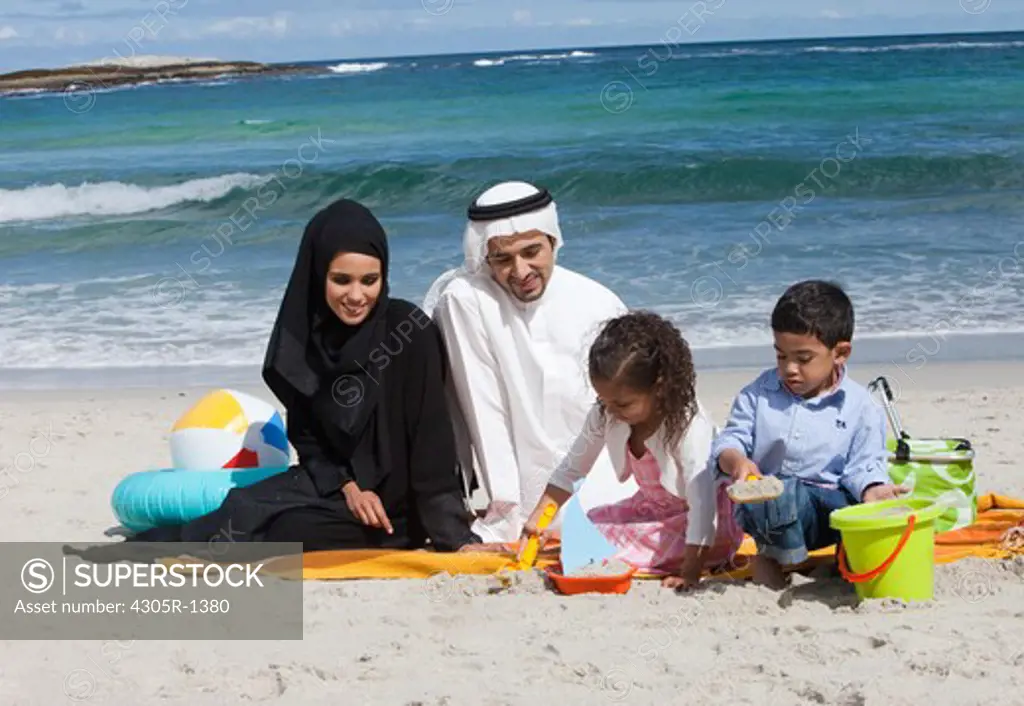 Arab family playing on the sand at the beach.