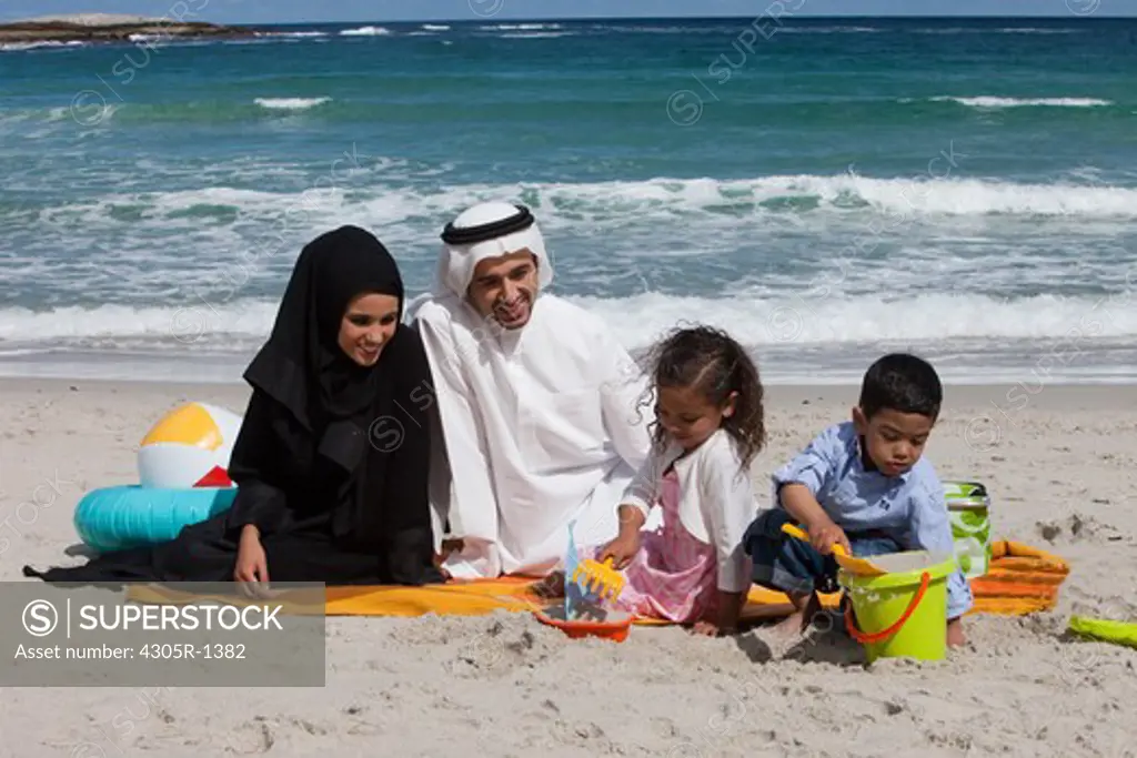 Arab family playing on the sand at the beach.