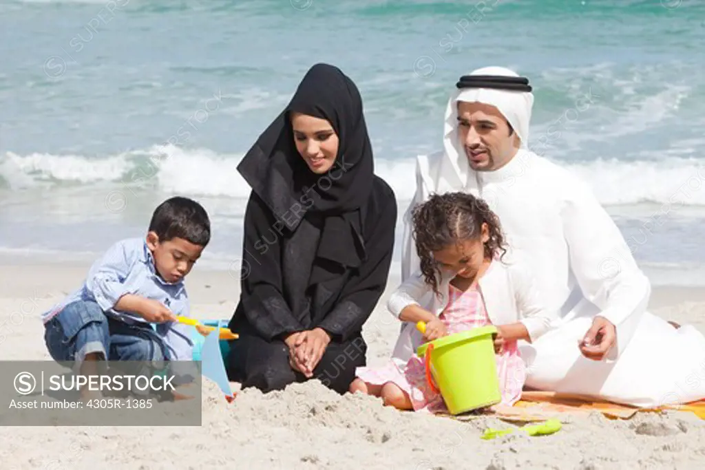 Arab family playing on the sand at the beach.