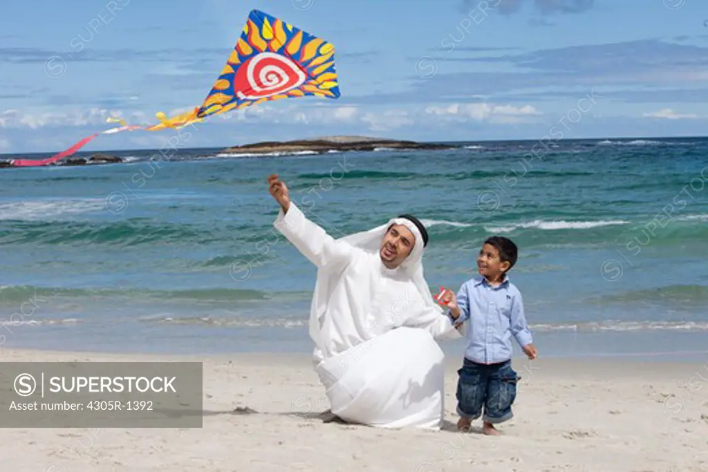 Arab father and son with kite walking at the beach.