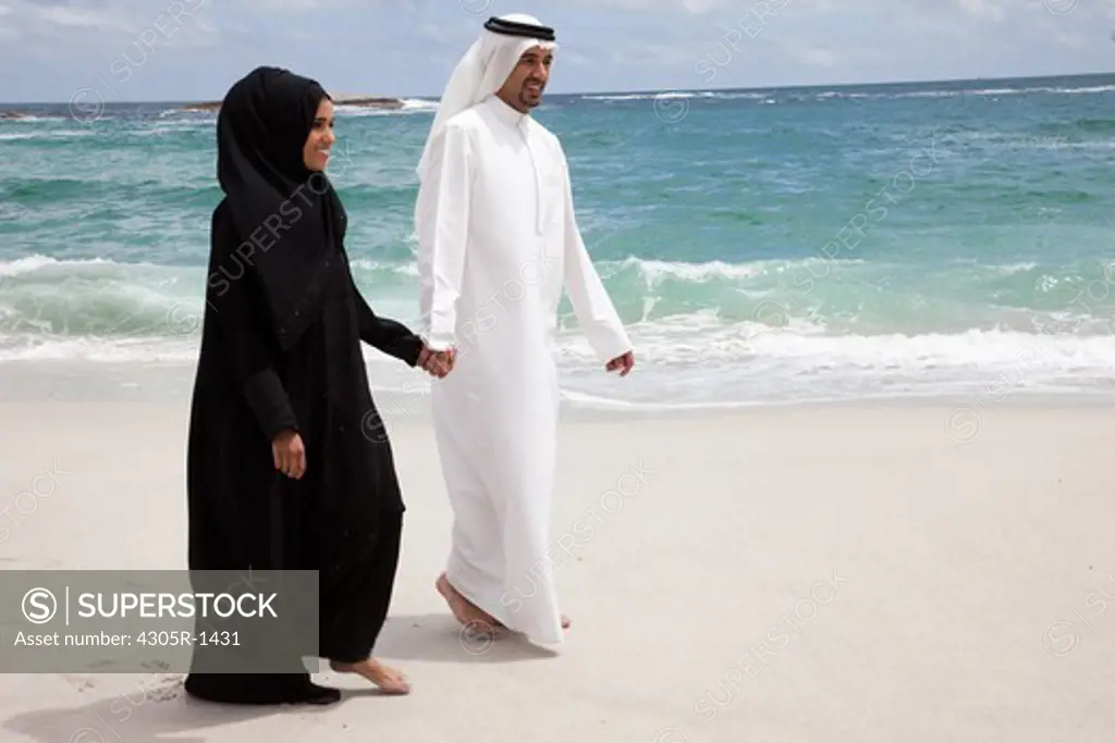 Young arab couple walking at the beach.