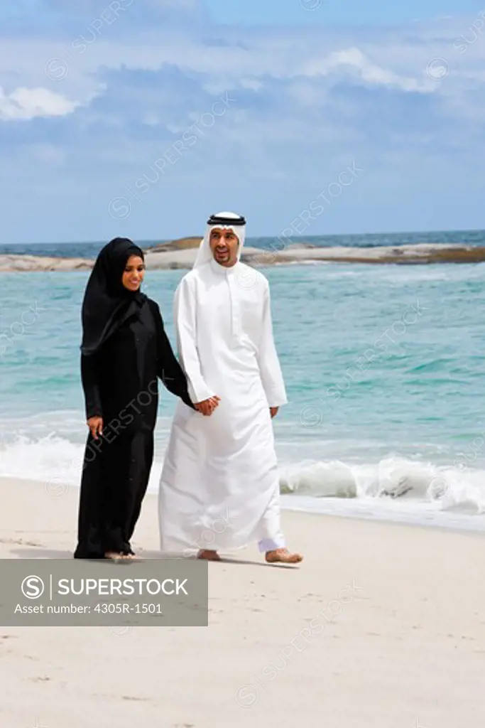 Young arab couple walking at the beach.