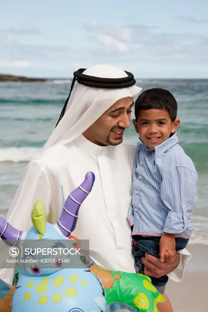 Arab father and son at the beach, smiling.