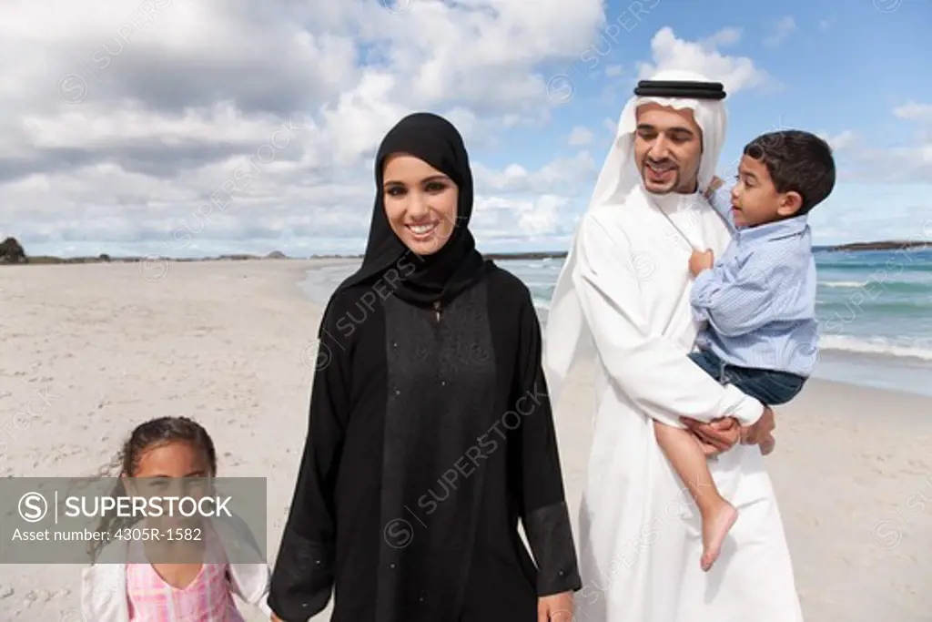 Portrait of arab family walking together at the beach, smiling.