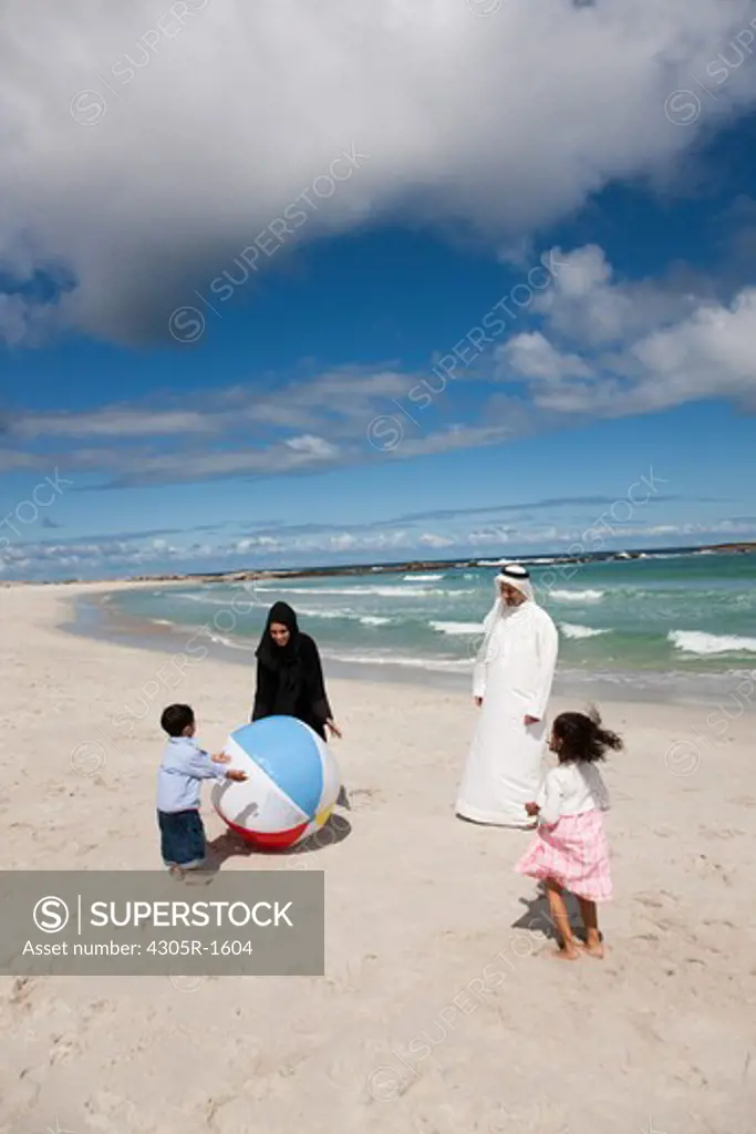 Arab family playing ball at the beach.