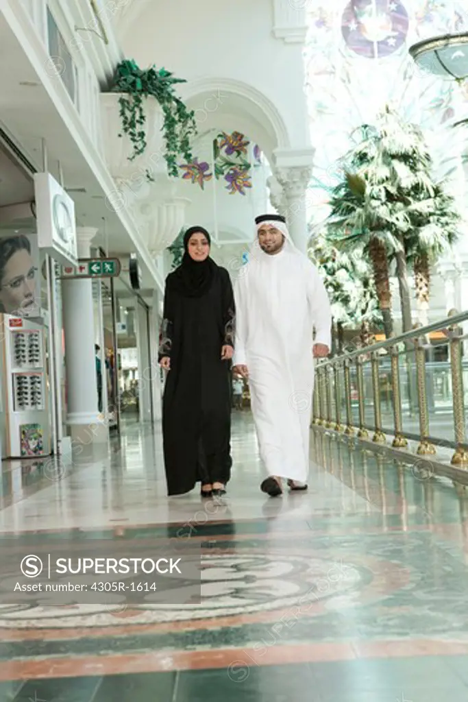 Arab couple walking in shopping mall.