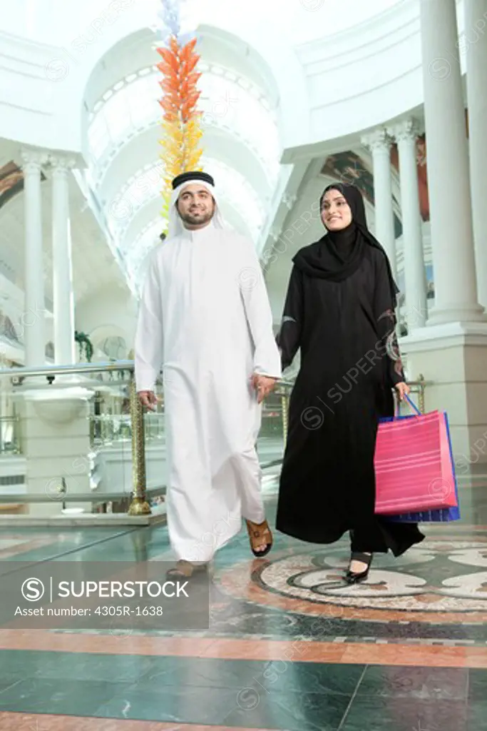 Arab couple with shopping bags walking in the mall.