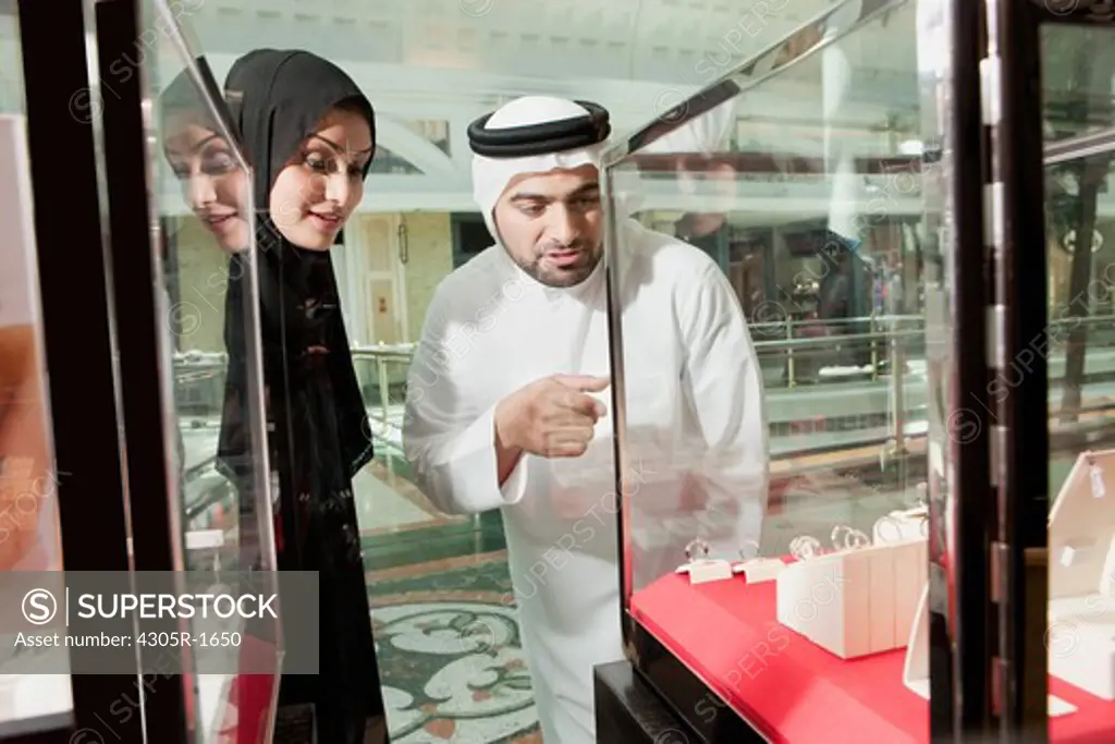 Arab couple in a jewelry store, man pointing.