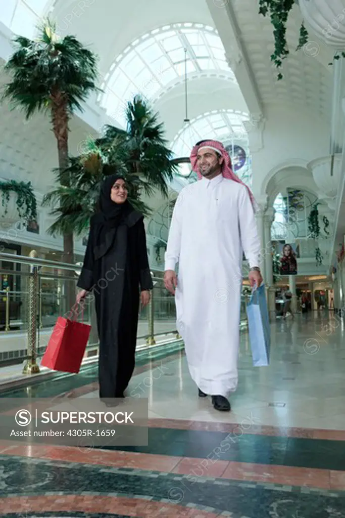 Arab couple with shopping bags walking in the mall.