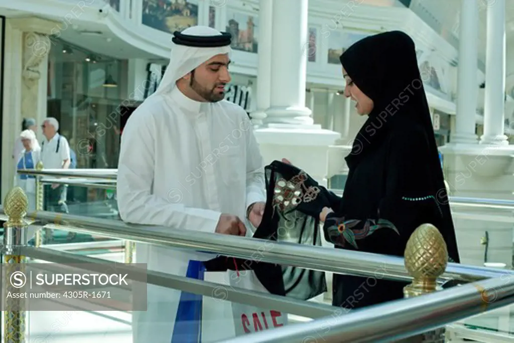 Arab couple in shopping mall, woman holding a scarf.
