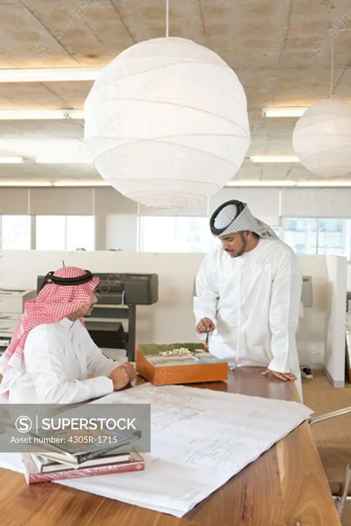 Two arab businessmen discussing over blueprint.