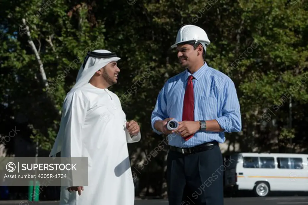 Arab businessman and architect talking and standing on street.