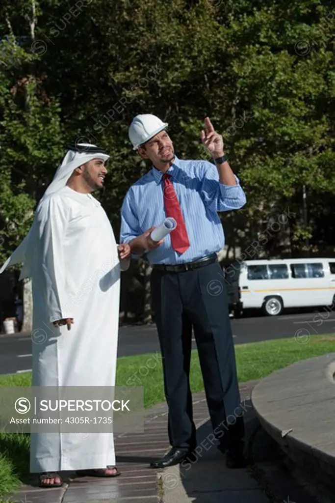Arab businessman and architect talking and standing on street.