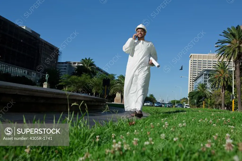 Arab architect with mobile phone, walking on street.