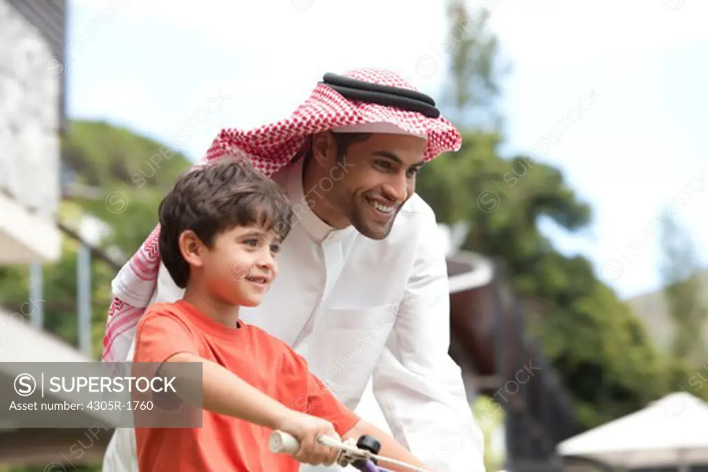 Arab father teaching his son how to ride a bicycle.