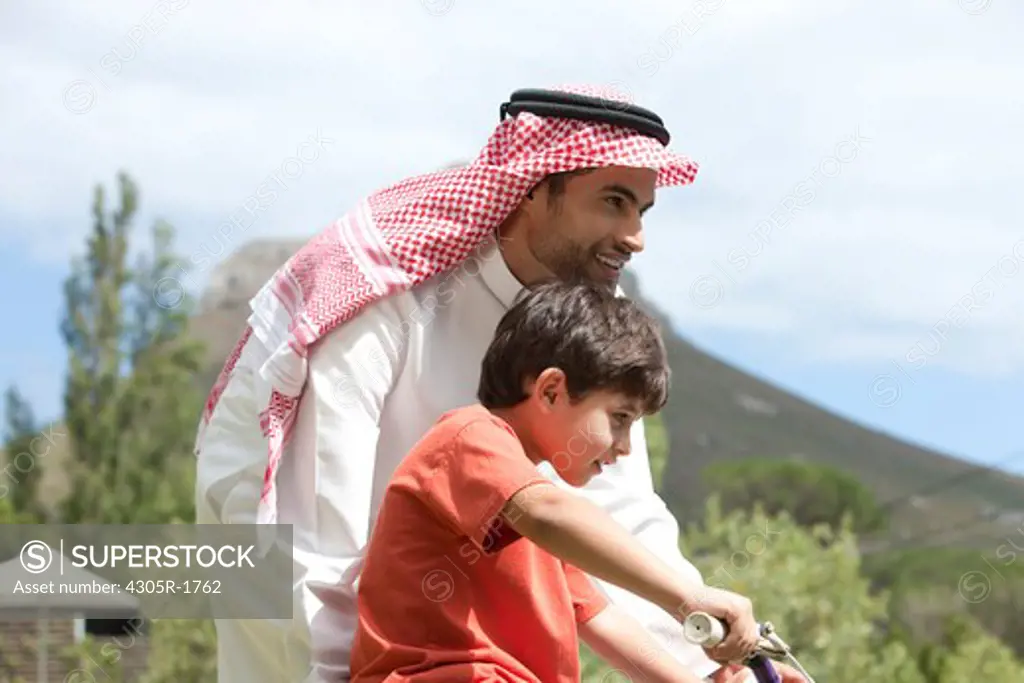 Arab father teaching his son how to ride a bicycle.