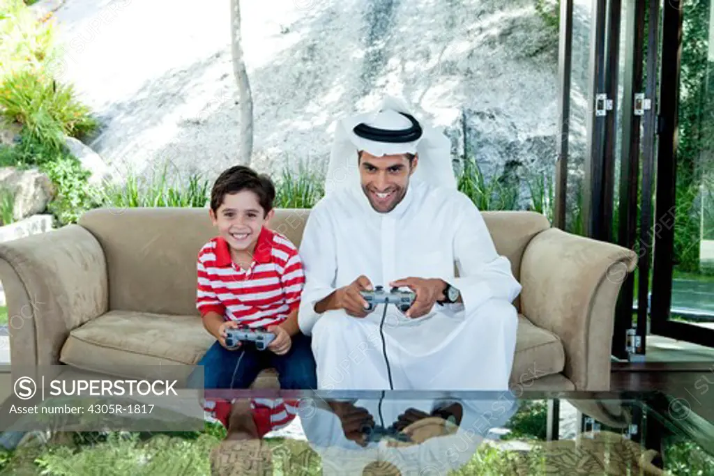 Arab father and son playing video game together.