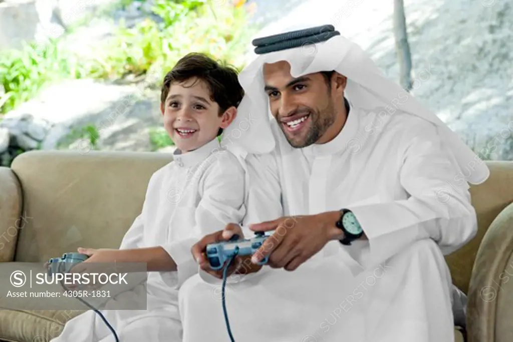 Arab father and son playing video game together.