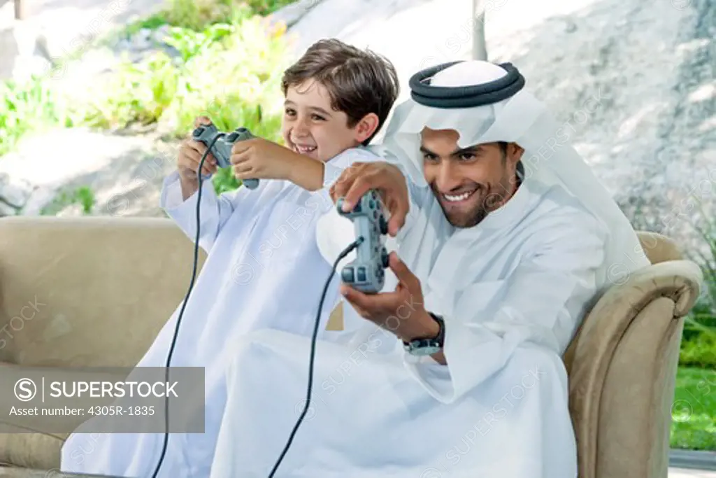 Arab father and son playing video game together.