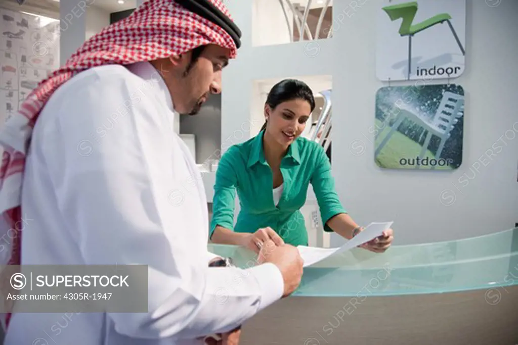 Receptionist assisting arab businessman with document.