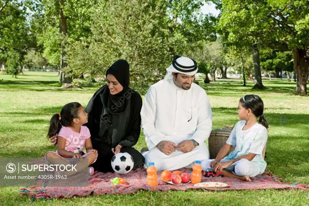 Arab family picnic in the park. Parents talking to their children.