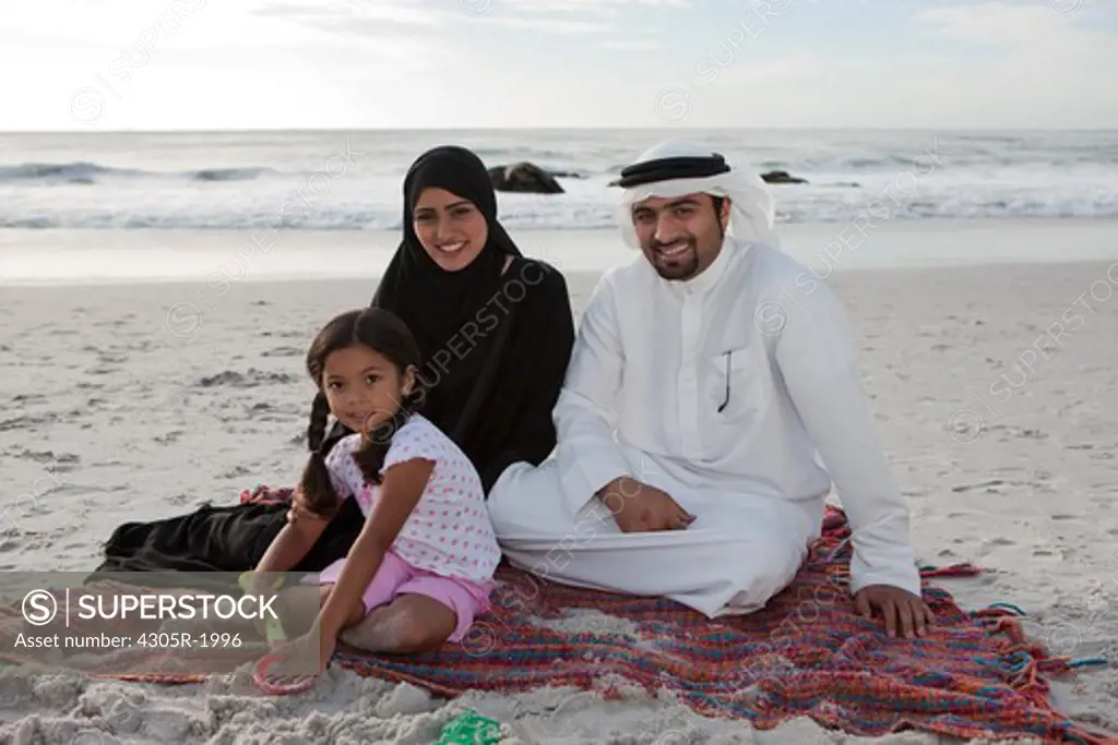 Portrait of arab family sitting by the beach.