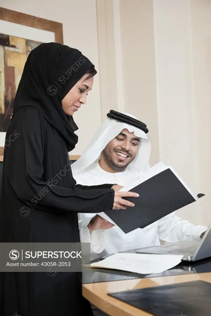 Arab businessman and businesswoman discussing in office.