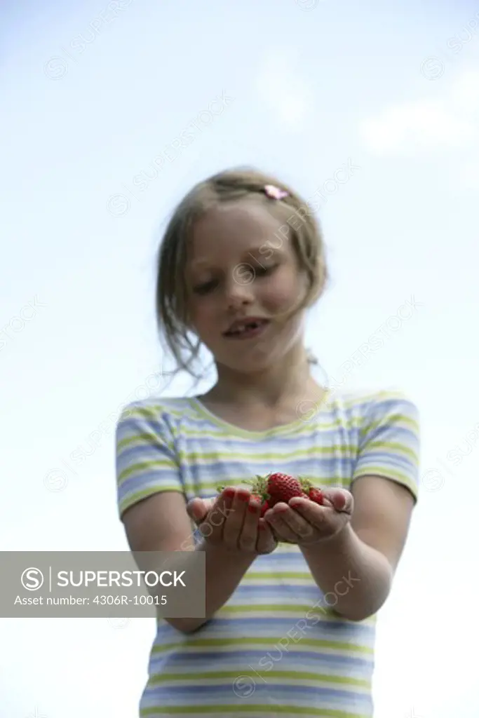 A girl with strawberries in her hands.