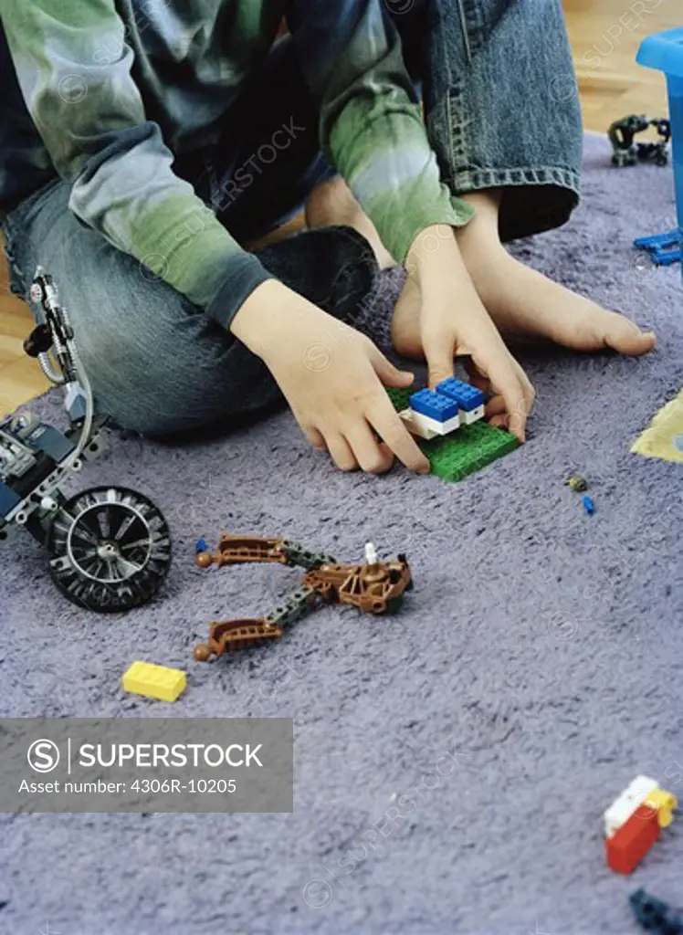 A boy sitting on the floor playing with lego.