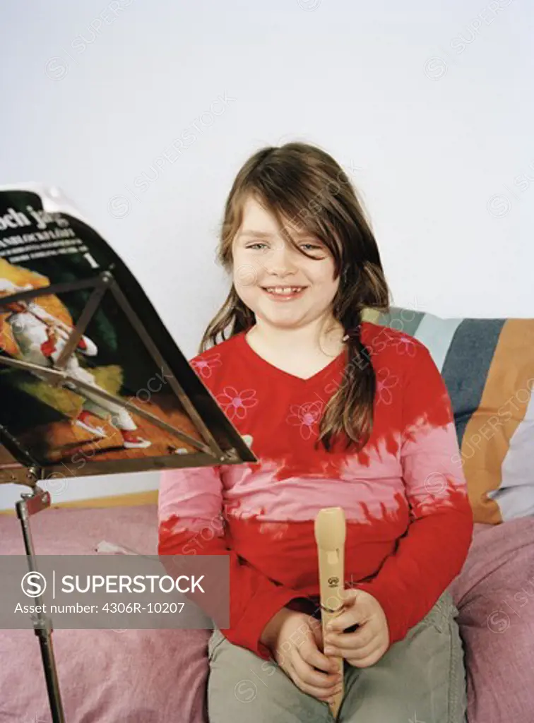 A girl with a flute sitting on a bed, Sweden.