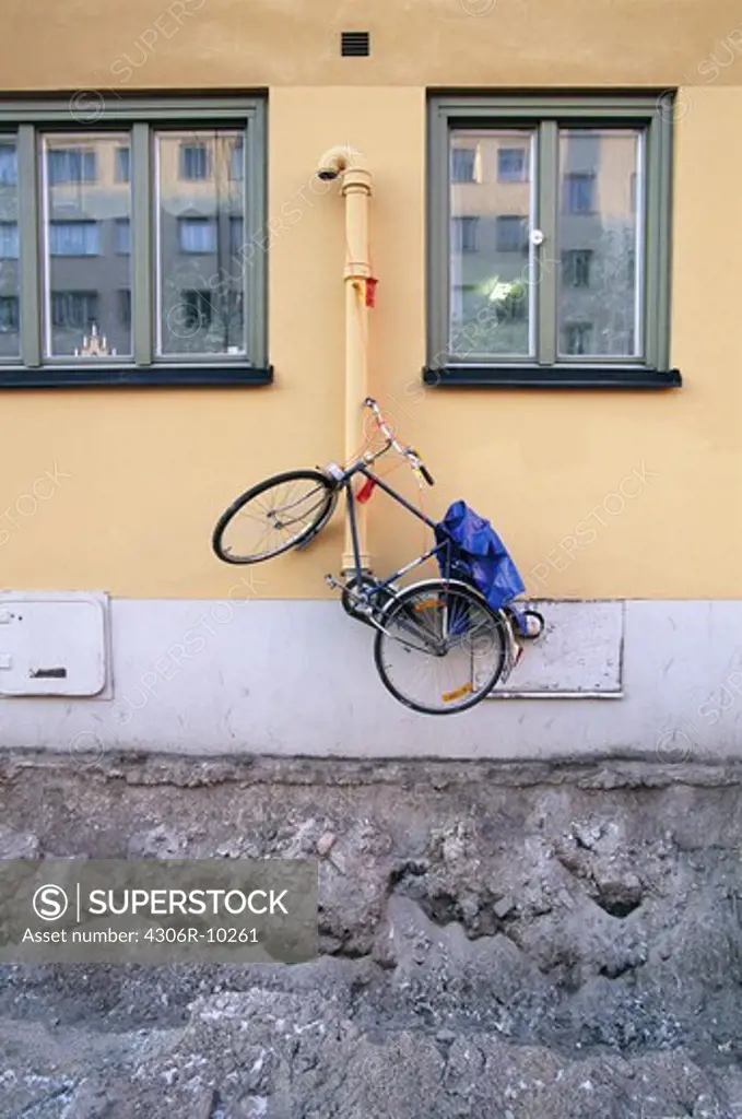 Bicykle hanging on a drainpipe.