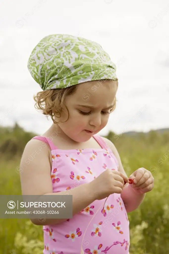 A girl making a straw of wild strawberries.
