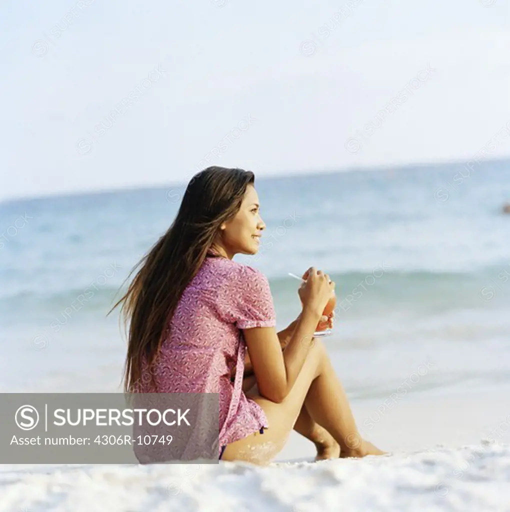 A woman sitting on the beach, Thailand.