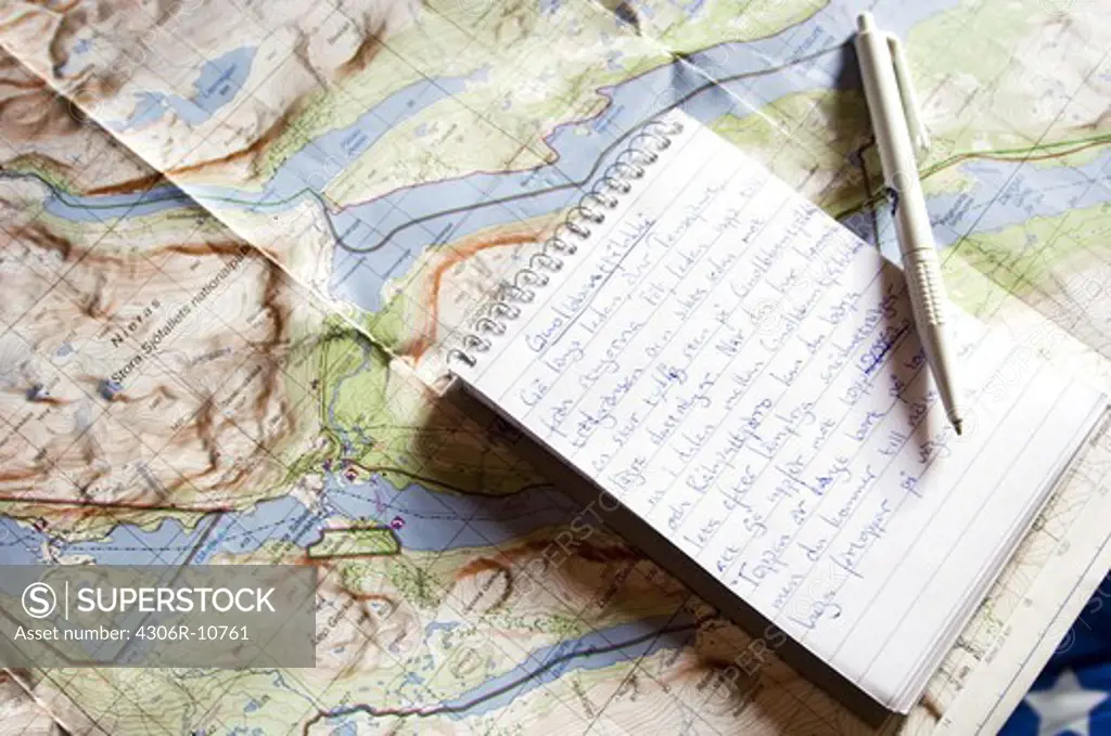 Notebook and pen on a map.
